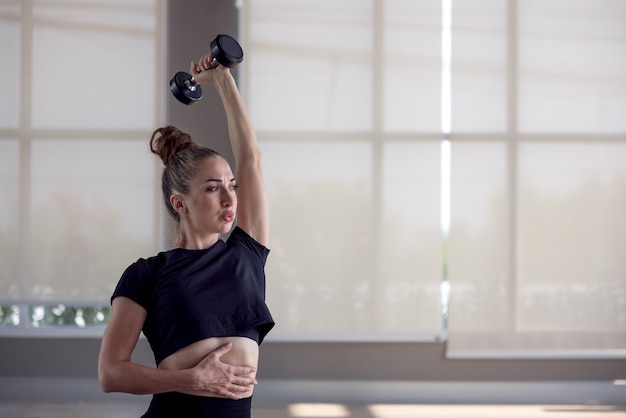 Fitness La femme sportive fait les exercices avec des haltères, force et motivation.