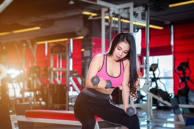 Fitness femmes asiatiques effectuant des exercices de formation avec haltère dans la salle de gym