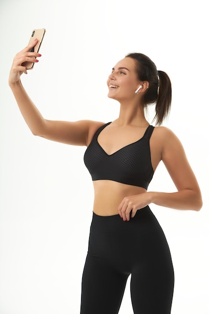 Fitness girl sur la formation en vêtements de sport tient un téléphone intelligent dans ses mains