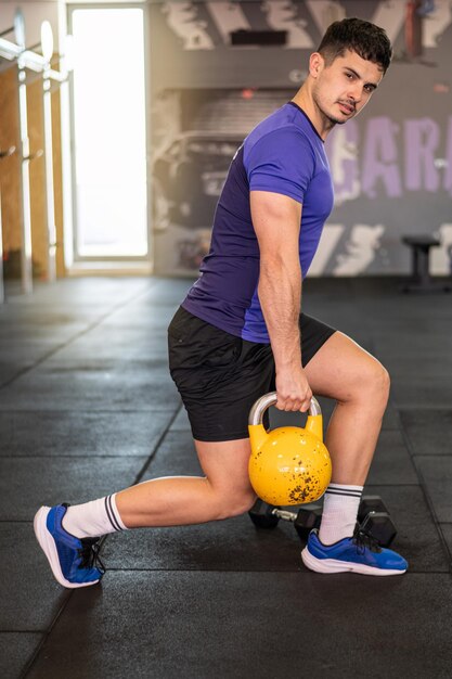 Fitness Kettlebell et entraîneur personnel avec un entraîneur d'homme formant une classe dans le gymnase pour la santé