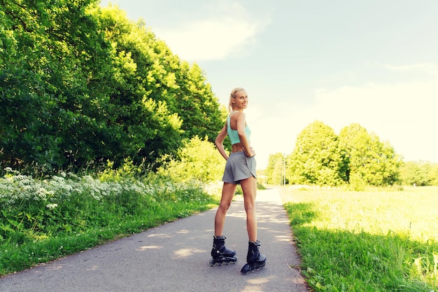 fitness, sport, été, patin à roues alignées et concept de mode de vie sain - jeune femme heureuse en patins à roulettes à l'extérieur