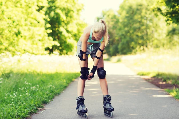 fitness, sport, été, patinage à roulettes et concept de mode de vie sain - jeune femme heureuse en patins à roulettes et équipement de protection à l'extérieur