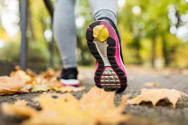 Photo fitness, sport, personnes, usure et concept de mode de vie sain - gros plan d'une jeune femme courant dans le parc d'automne