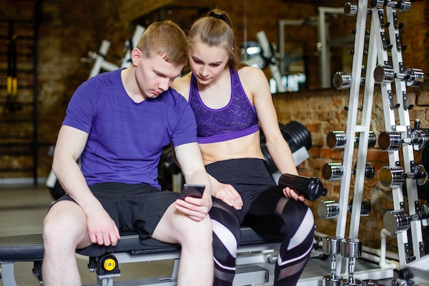 Fitness, Sport, Technologie Et Amaigrissement - Femme Et Entraîneur Personnel Avec Smartphone Et Gourde Dans La Salle De Sport