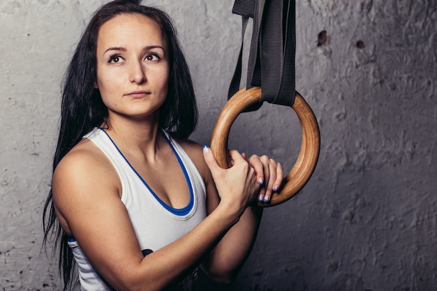 Fitness woMan bras d'entraînement avec anneaux de gymnastique dans le gymnase