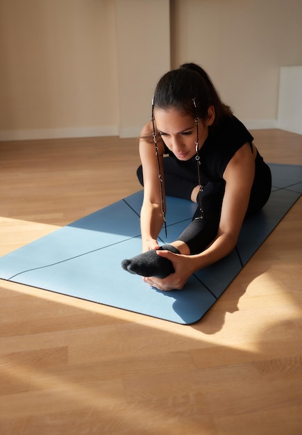 Fitness workout girl s'accroupit sur le tapis à la maison vue de côté