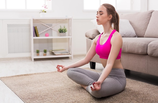 Fitness, yoga femme relax méditation en posture de lotus à la maison, gros plan. Jeune fille mince fait de l'exercice.