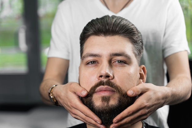 Fixer la forme de la barbe avec de la cire. Le résultat d'une coupe de cheveux dans un salon de coiffure.