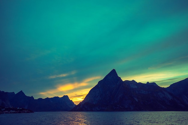 Fjord au coucher du soleil Plage rocheuse en soirée Silhouette de rochers contre ciel coucher de soleil coloré Lofoten Reine Norvège