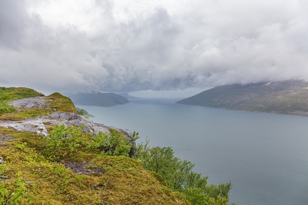 Fjord norvégien et montagnes entourées de nuages, reflet idéal du fjord dans l'eau claire