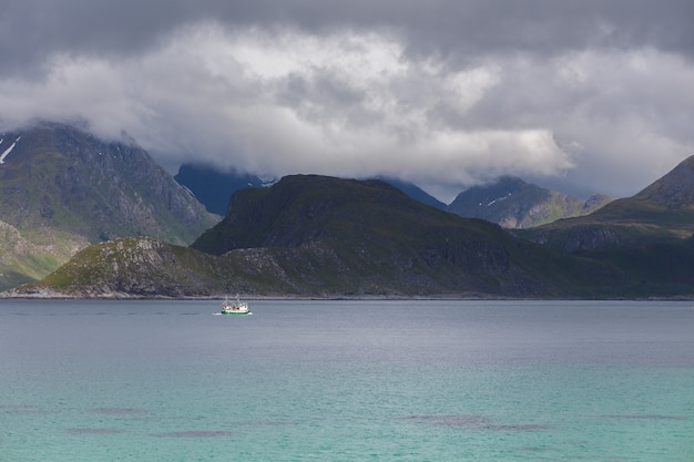 Fjord norvégien et montagnes entourées de nuages, reflet idéal du fjord dans l'eau claire