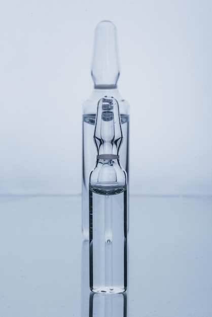 Flacon d'ampoule médicale en verre pour injection Le médicament est un médicament blanc sec en poudre de pénicilline ou liquide avec une solution aqueuse en ampoule Gros plan Bouteilles ampoule avec bouchon en aluminium sur fond gris