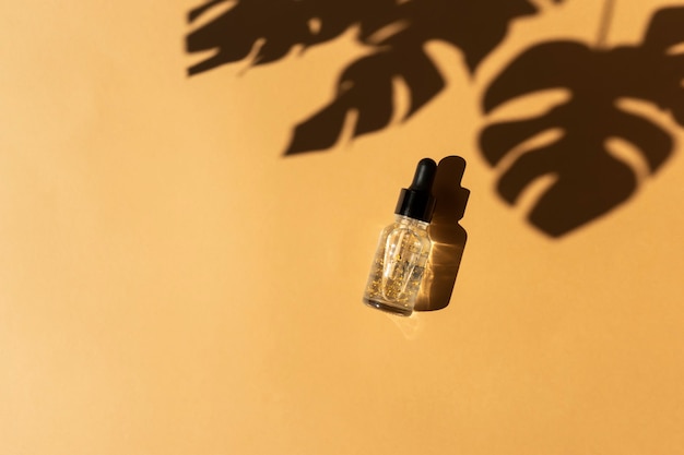 Un flacon compte-gouttes d'huile essentielle transparente avec des parties dorées. Concept de cosmétiques naturels