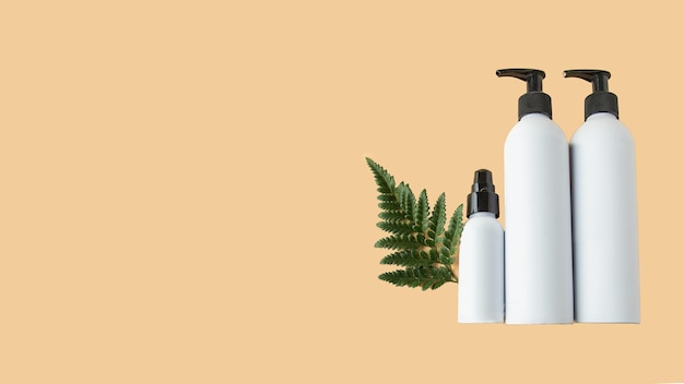 Flacon cosmétique blanc sur fond beige avec feuille verte Mocke pour la marque cosmétique naturelle