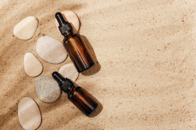 Flacon cosmétique avec une pipette sur le sable. sur fond de sable.