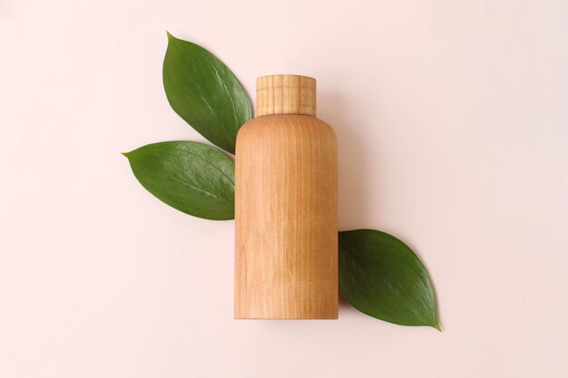 Flacon de cosmétiques en bois naturel sur fond beige avec des feuilles fraîches et juteuses