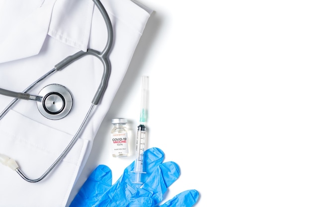 Un flacon du vaccin Covid 19 avec seringue et stéthoscope sur chemise chemise isolé sur fond blanc, prévention du coronavirus ou concept d'épidémie de COVID-19