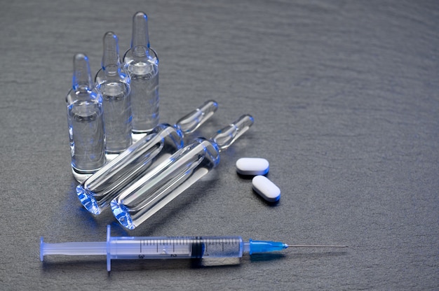 Flacon médical et ampoules pour injection et seringue et pilules sur la surface de la table brillante grise avec espace de copie