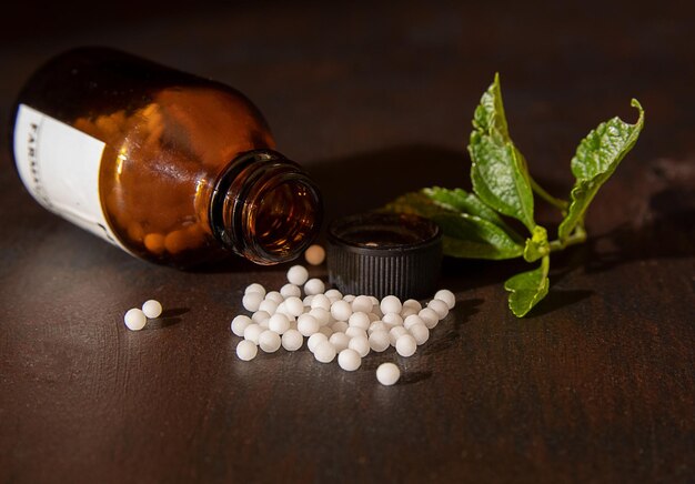 Photo un flacon de médicament avec des boules blanches dessus et une feuille verte sur le côté.