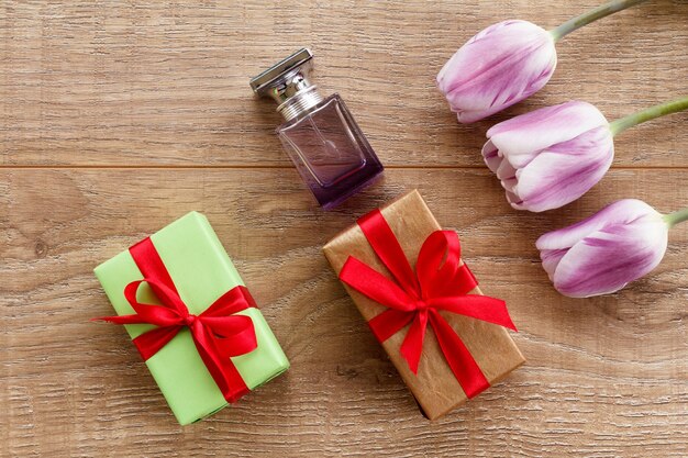 Flacon de parfum et coffrets cadeaux sur des planches en bois avec des fleurs