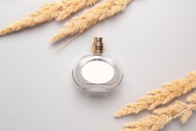 Flacon de parfum avec étiquette blanche et herbe de pampa Concept de parfum et de cosmétiques coûteux Parfum floral pour femme Vaporisateur de parfum Parfum de toilette de luxe moderne pour femme