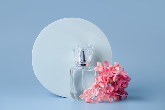 Flacon de parfum et fleurs roses avec espace de copie sur fond bleu