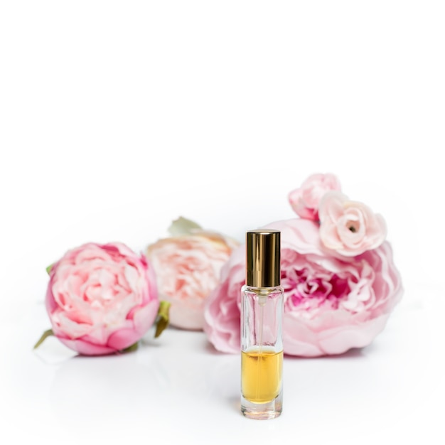 Flacon de parfum avec des fleurs sur une surface légère