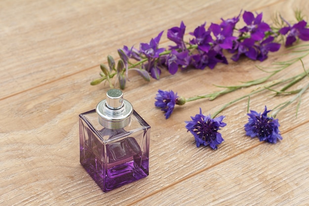 Flacon de parfum et fleurs violettes sur les planches de bois. Concept de donner un cadeau en vacances. Vue de dessus.