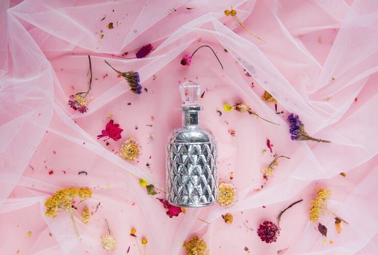 Photo flacon pefume et fleurs séchées sur tulle rose. lumière naturelle