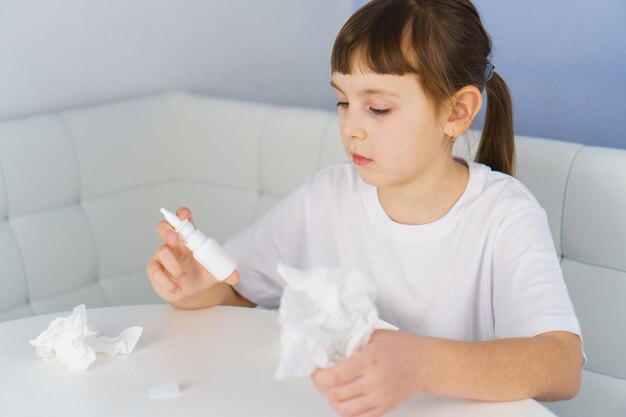 Flacon pulvérisateur nasal et mouchoir en papier dans les mains des filles Traitement de la sinusite virale et bactérienne allergique