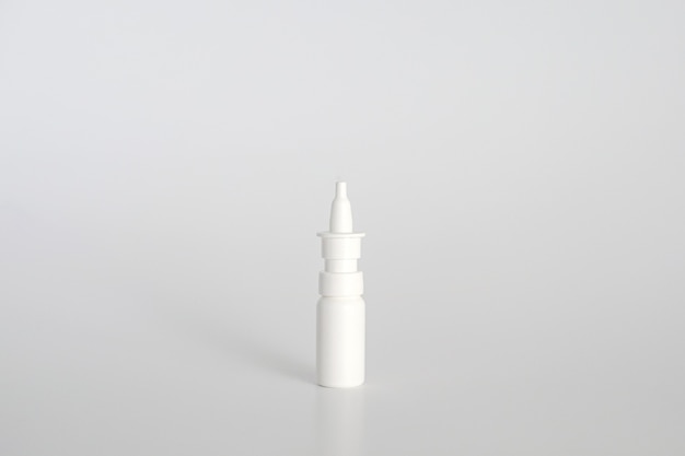 Flacon pulvérisateur nasal en plastique blanc sur fond blanc. Vaporisateur nasal, solution d'eau saline pour le traitement de la congestion nasale. Nez qui coule, rhumes. Espace libre, espace de copie.