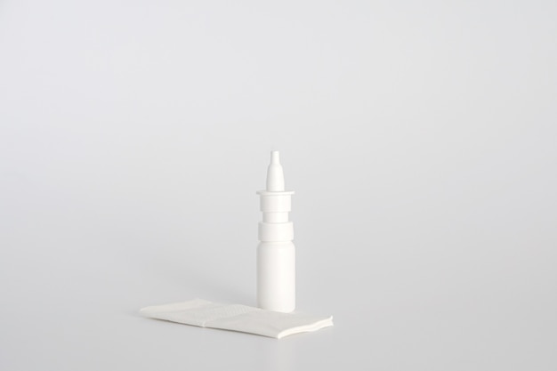 Flacon pulvérisateur nasal en plastique blanc sur fond blanc. Vaporisateur nasal, solution d'eau saline pour le traitement de la congestion nasale. Nez qui coule, rhumes. Espace libre, espace de copie.