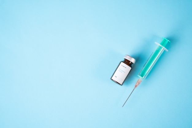 Un flacon de vaccin contre le coronavirus une seringue avec une aiguille avec un fond bleu Copyspace