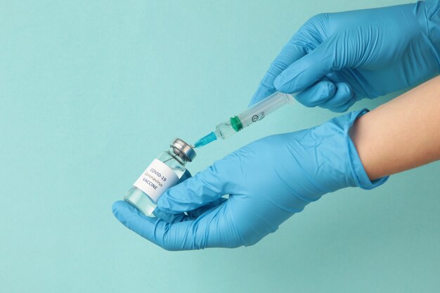 Flacon avec vaccin contre le covid 19 et seringue à la main du chercheur portant des gants