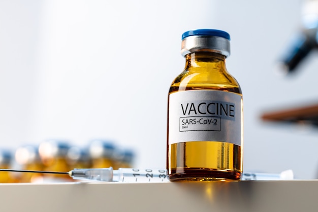 Flacon de vaccin Covid-19 avec une seringue sur table de laboratoire