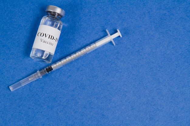 Flacon de vaccin Covid19 et seringue pour injection sur fond bleu Traitement de vaccination SARSCoV2 Vue de dessus espace de copie