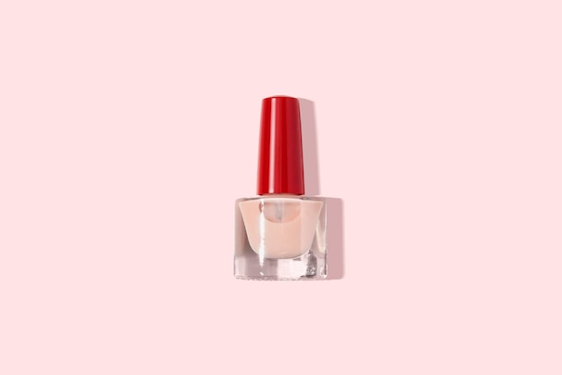 Flacon de vernis à ongles beige sur fond rose pastel