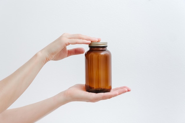 Flacon en verre brun vide médical avec bouchon dans les mains Mokup fond blanc Alternative et à base de plantes