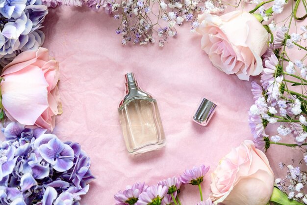 Flacon en verre de parfum avec des fleurs autour de la mise à plat sur la vue