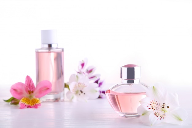 Flacons de parfum avec des fleurs sur blanc