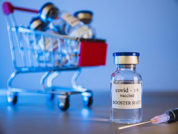Flacons de vaccin de rappel COVID-19 dans le panier. Concept de médecine et de soins de santé