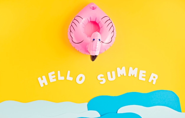 Flamant rose gonflable, vagues de mer en papier et texte bonjour l'été. Vacances d'été et plage, vacances à la mer, concept de fêtes