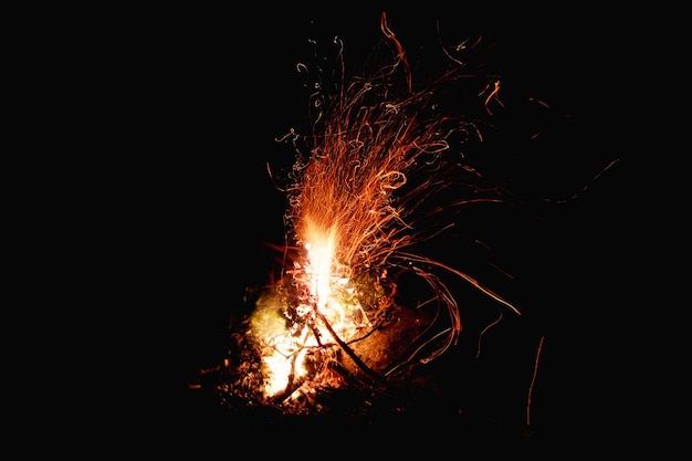 Flammes de feu de camp avec des étincelles sur un fond sombre