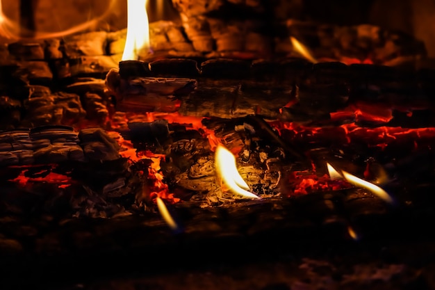 Flammes de feu et charbons ardents de bois brûlé dans la cheminée