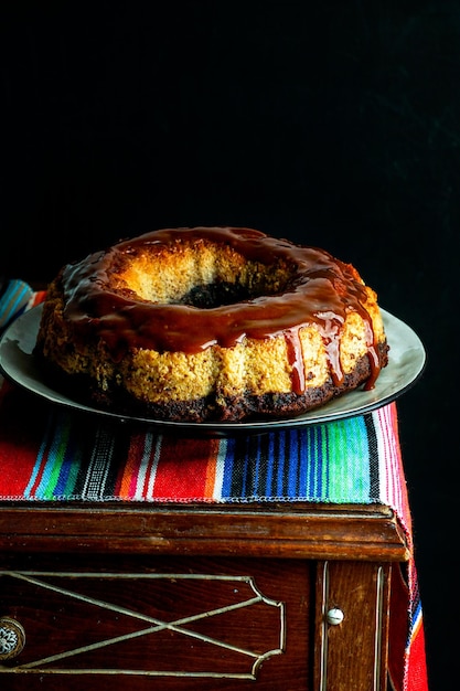 flan au chocolat, chocoflan mexicain, gâteau au biscuit au chocolat et pudding à la crème au caramel avec une sauce au caramel sur le dessus, sur une table en bois sombre