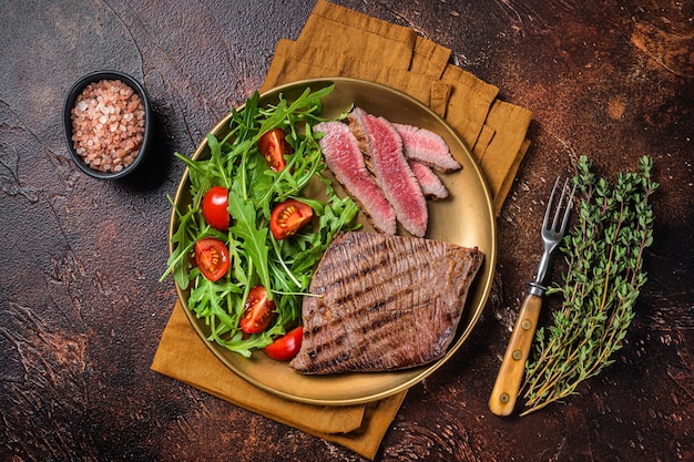 Flanc rôti ou Flap Steak dans une assiette avec salade Fond sombre Vue de dessus