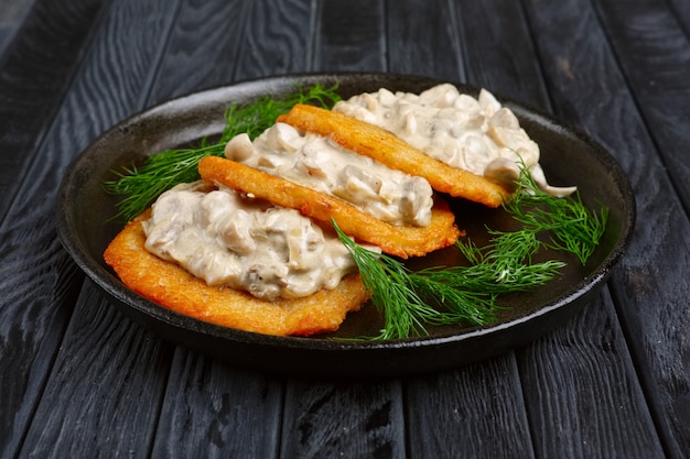 Flanjack de pommes de terre (draniki) avec sauce crémeuse à l&#39;oignon et aux champignons dans une poêle en fonte