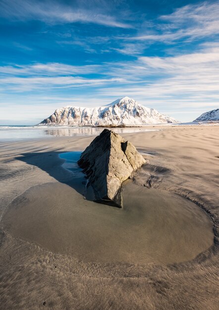 Flaque de sable et rocher avec montagne enneigée