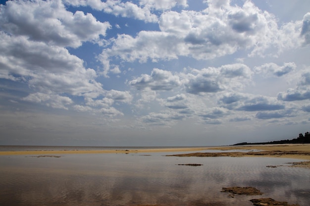 Flaques d'eau sur la plage reflétant les nuages d'un ciel couvert