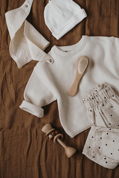 Flatlay esthétique scandinave bébé nouveau-né vêtements accessoires jouets sur fond marron ensemble de luxe élégant pour bébé à la mode vue de dessus